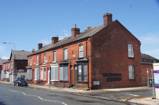 Boarded-up red-brick terraced houses on a street corner in Liverpool.