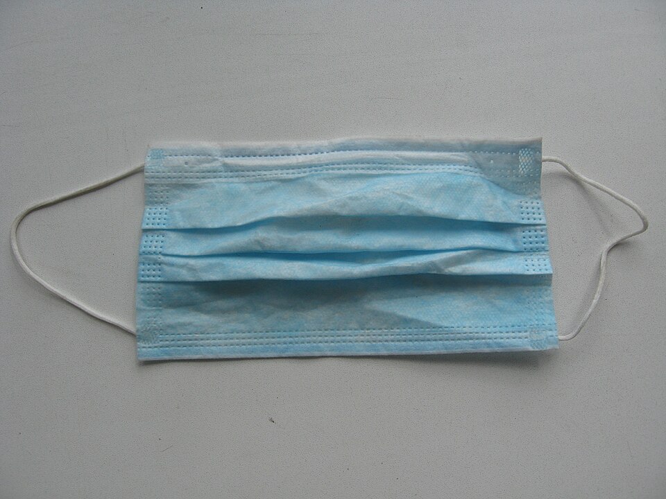 A blue disposable medical face mask with ear loops.