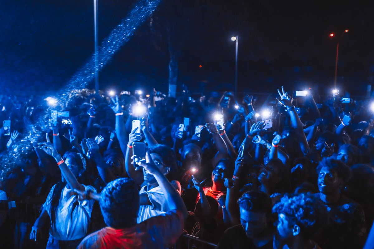 A large crowd at a night-time event with stage lighting — the kind of enhanced-tier gathering that attracts the fuller duty.