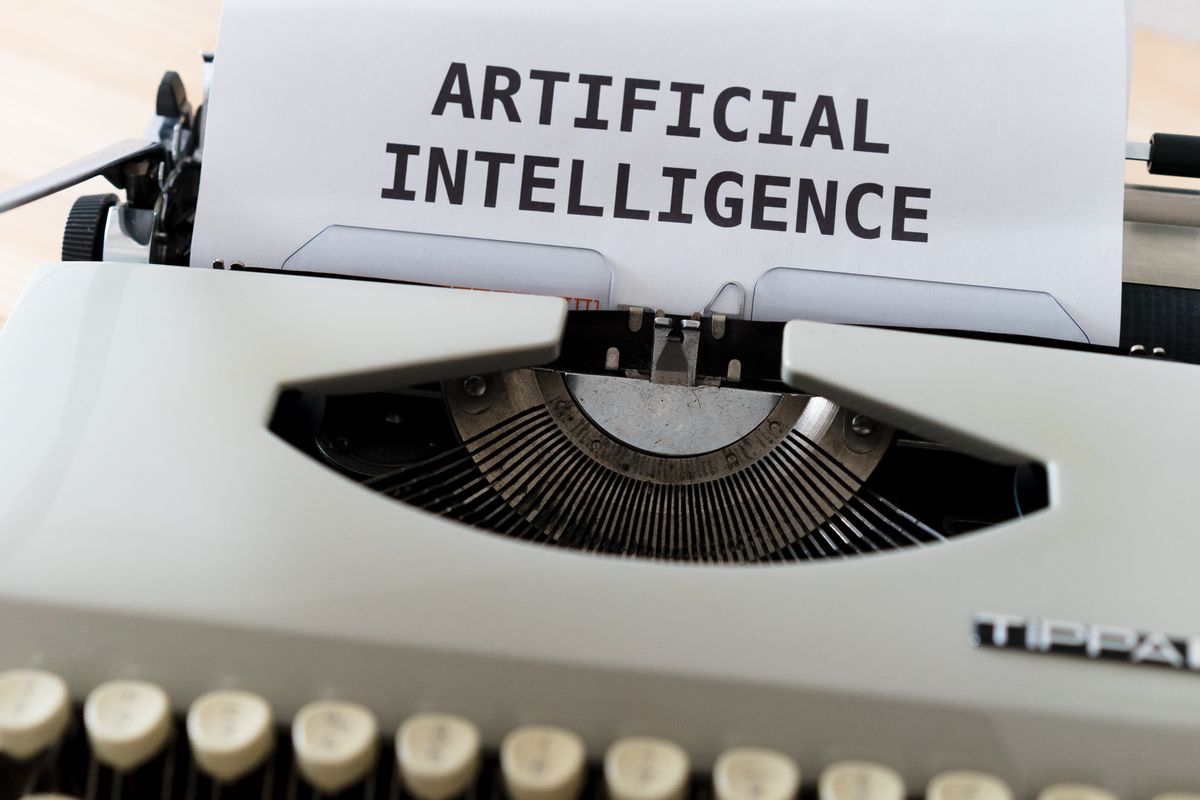 A sheet of paper in a typewriter bearing the words ARTIFICIAL INTELLIGENCE.