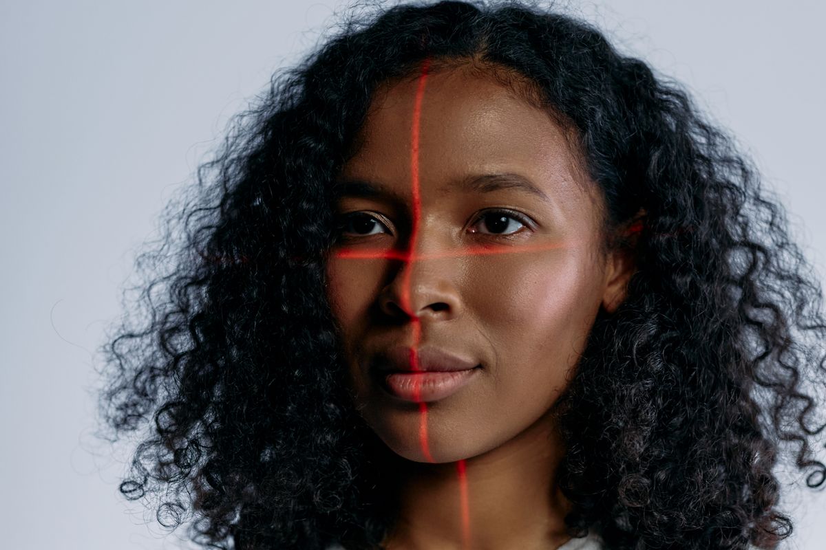 A person's face overlaid with laser scanning lines, representing biometric facial recognition.
