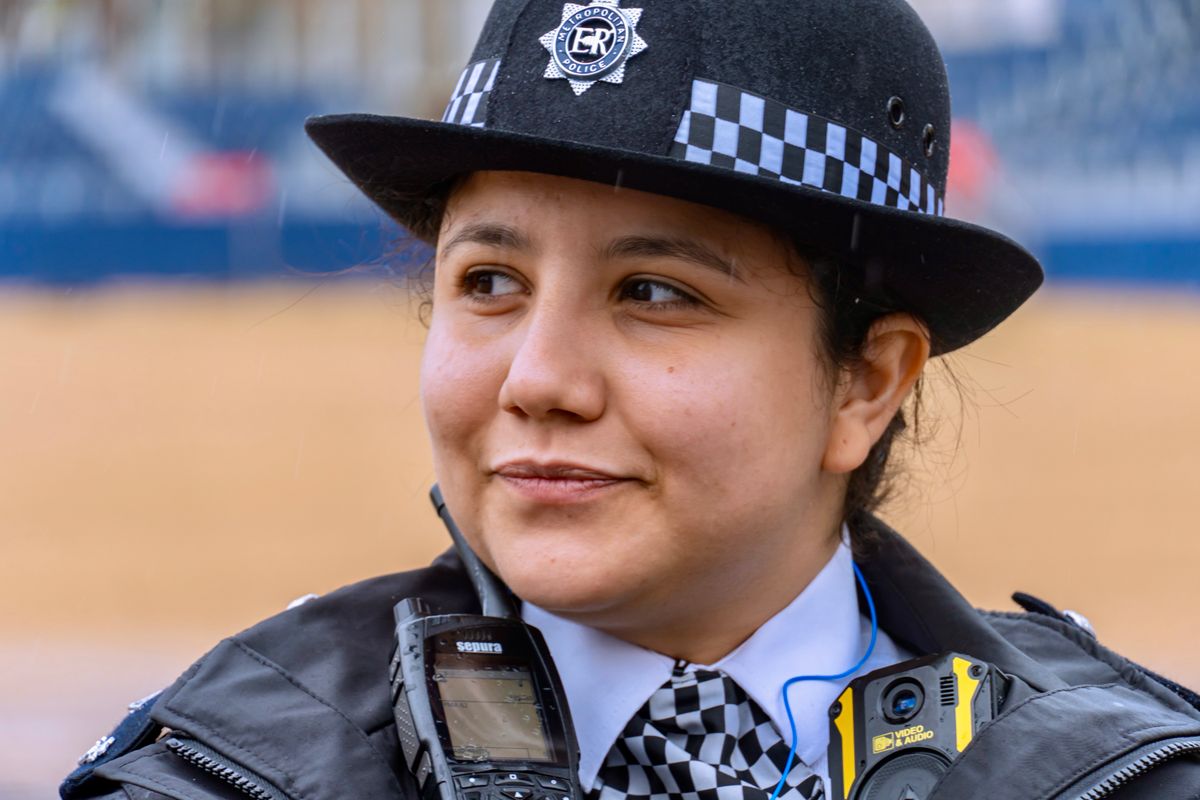A Metropolitan Police officer in a custodian helmet, with radio and body-worn camera visible.